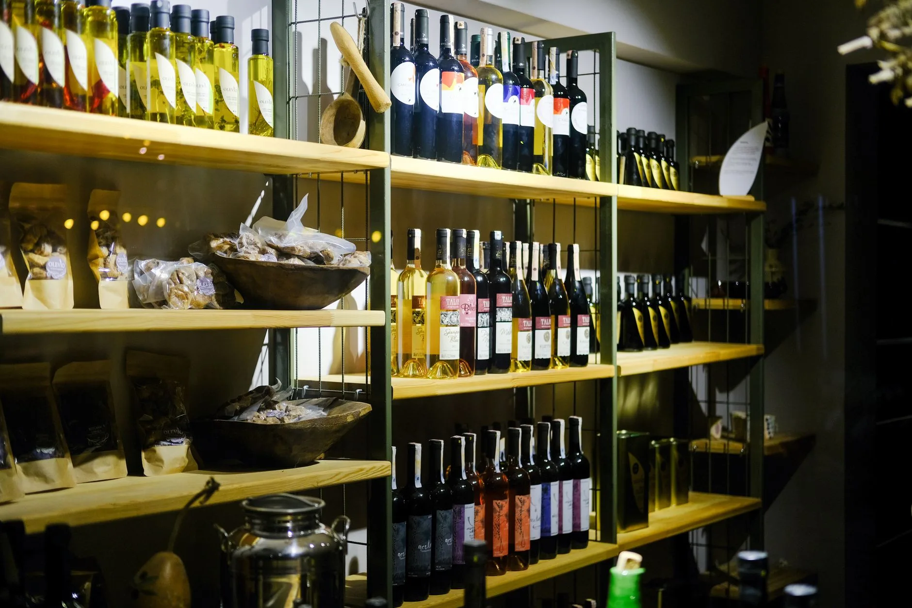 A variety of wine bottles displayed on wooden shelves in a Bozcaada retail store.