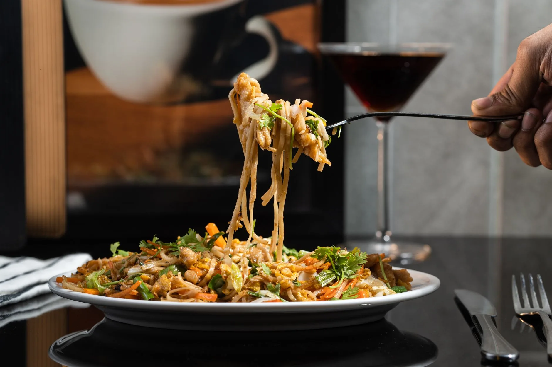 Delicious noodles elegantly served on a plate, complemented by a refreshing beverage in the background.